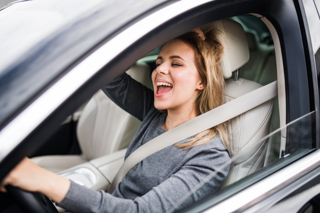 cheerful-young-woman-driver-sitting-in-car-drivin