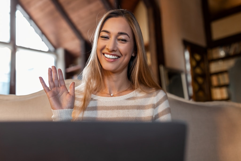 smiling-woman-working-on-laptop-waving-hand-2022