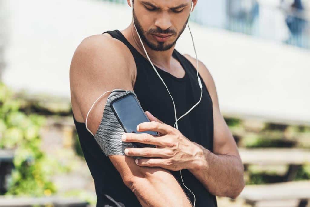 serious young sportsman in earphones with smartpho