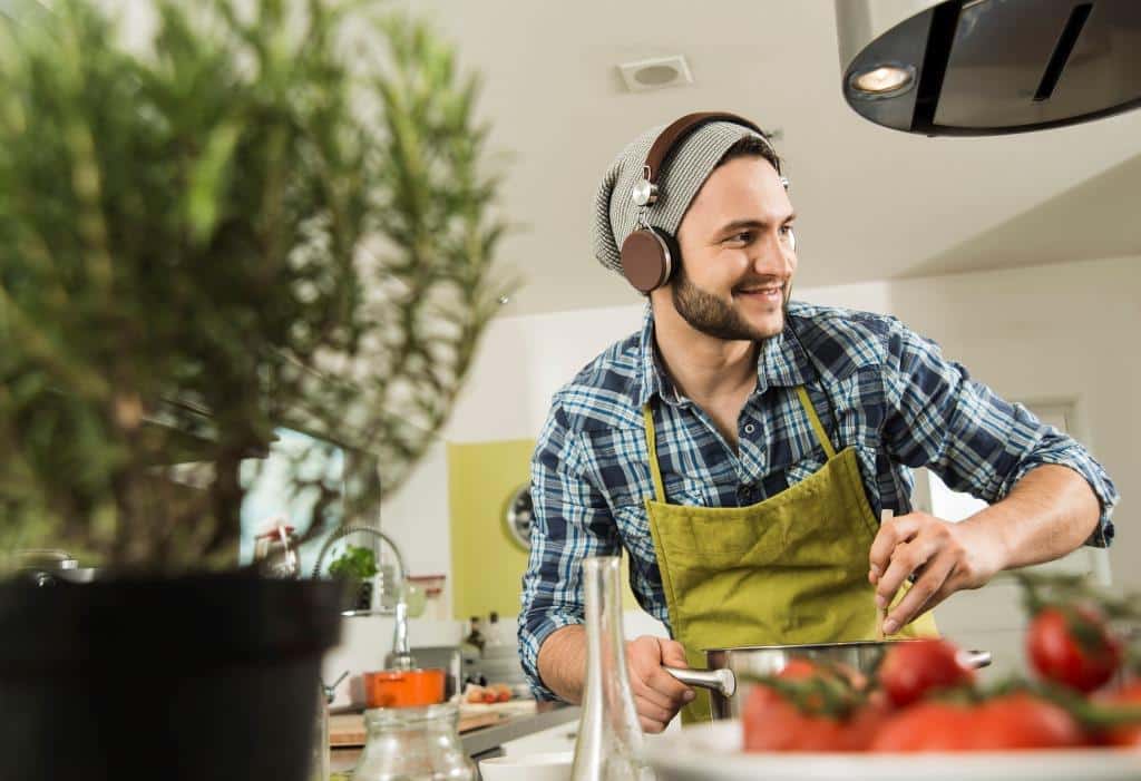 young man with headphones cooking in kitchen at home