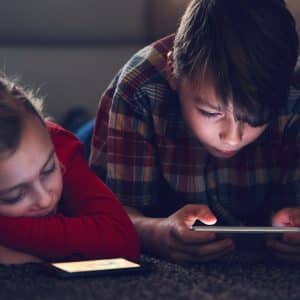 Little girl and boy watching video or playing games on their smart phones